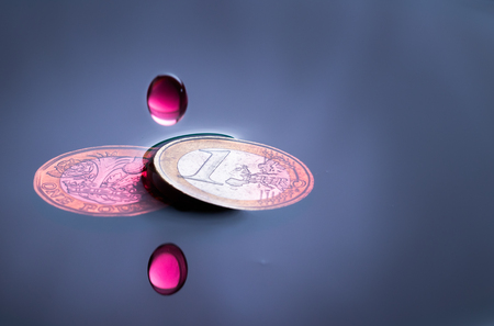 blood colored water drop falling and impacting a euro coinの写真素材