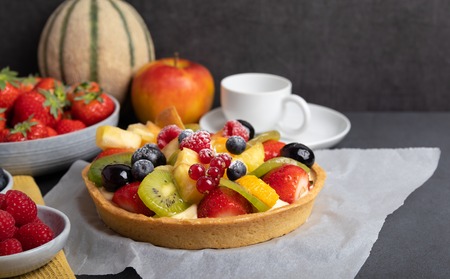 homemade fruit pie with strawberries,raspberries,blueberries,kiwi,melon and apple on a rustic tableの写真素材