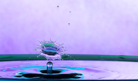 Macro close up of a water drop impacting a body of water and colliding with another water droplet