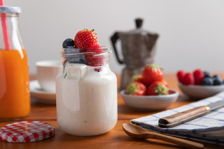 Yogurt with strawberries, raspberries and blueberries on a breakfast table.の写真素材
