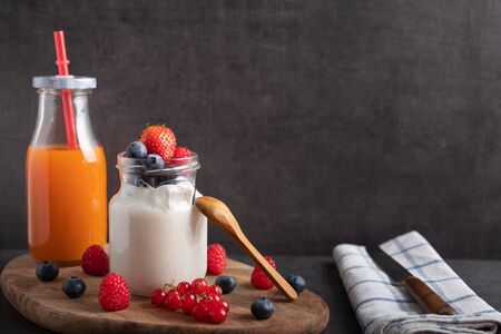 Yogurt with strawberries, raspberries and blueberries on a breakfast table.の写真素材