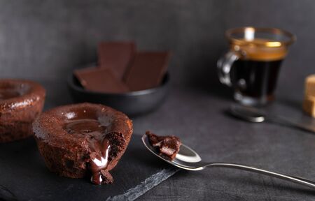 Homemade chocolate lava cake on a black plate with a coffee on a black backgroundの写真素材