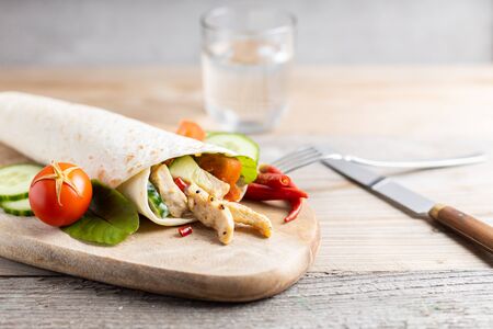 Chicken doner kebab with fresh vegetables on a wooden table with a glass of wine.の写真素材