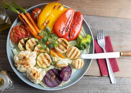 Organic grilled vegetables bell pepper, cauliflower,broccoli,carrots,mushrooms and red onions served on a round plate. Vegetarian dinner serving of roasted vegetables. Top view.の写真素材