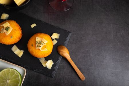 Homemade croquettes filled with cheese with lemon and a glass of red wine.の写真素材