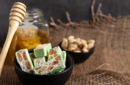 Organic nougat made with honey, pistachio, hazel nut, and almond nuts on a rustic dark background.の写真素材