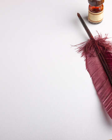 feather quill and inkwell on a white paper with copy spaceの写真素材