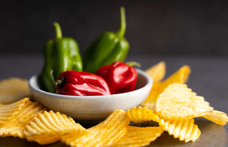 Homemade hot chips with jalapeno peppers on the side. On a dark colored table top.の写真素材