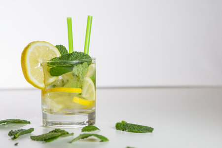 healthy lemon drink with some lemons and mint leaves and white background. horizontal plus copy space rightの写真素材
