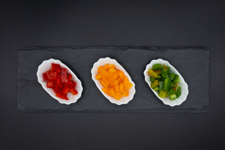 small bowls with healthy red, green, and red peppers cut into cubes with black background format. Horizontally photographed from above.の写真素材