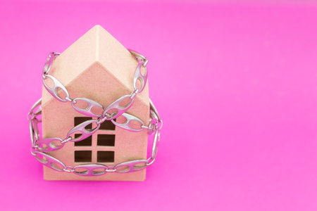 House cordoned off for quarantine measures with steel chain at times. Horizontal format with pink background and copy space on right sideの写真素材