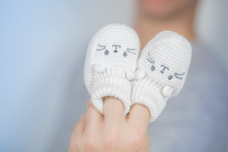 pair of white newborn shoes sticked on finger. horizontal