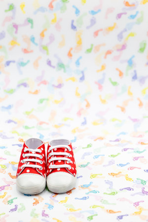 pair of newborn shoes in red with white dots on colorful background plus copy space. Verticalの写真素材