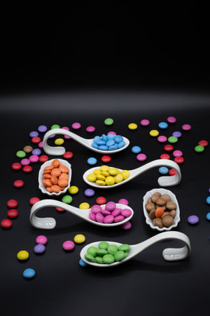 tryspoon for bithday buffet or party with smarties in many different colors on black background. Verticalの写真素材