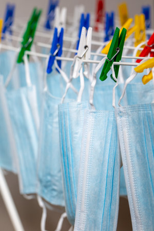 Clothes rack with washed blue one-time masks at home in virus times. Vertical formatの写真素材