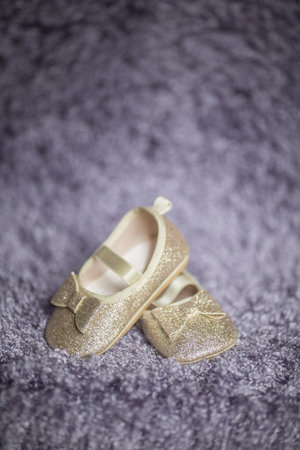 pair of golden child girl newborn shoes on a fur background. verticalの写真素材