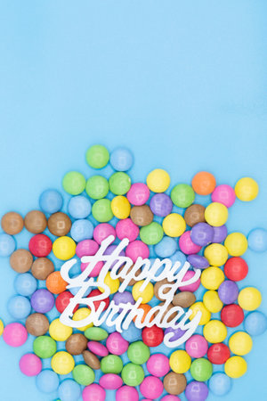 Colorful Card for birthday party invitation with sweets and the words happy birthday on blue background verticalの写真素材