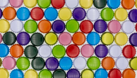 Crown corks and caps in various colors, such as blue, red, orange and gold. Lined up as a colorful...