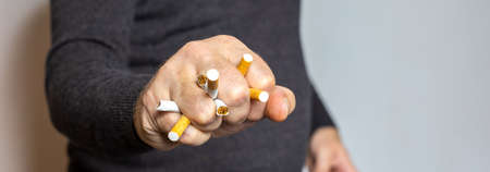 Man stops smoking and crushes cigarettes with his fist, symbolic of quitting smoking