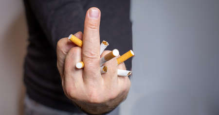 Man stops smoking, shows cigarettes his middle finger and destroys the cigarettes in his hand and crushes themの写真素材