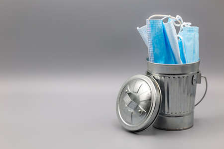 Silver garbage bin with lid filled with medical face masksの写真素材