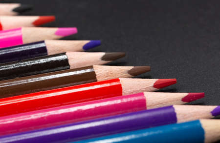 Close-up of colored pencils slanted together with black background and some copy space for school and artの写真素材