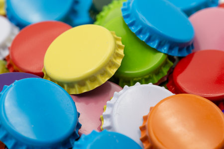 Close-up of colorful crown corks in yellow, green, blue and red lying on top of each other as backgroundの写真素材