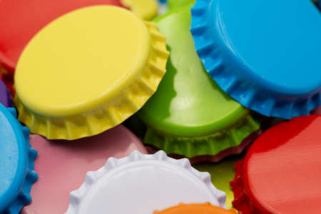 Close-up of different colored crown corks in yellow, red and blue lying on top of each other to use as a backgroundの写真素材