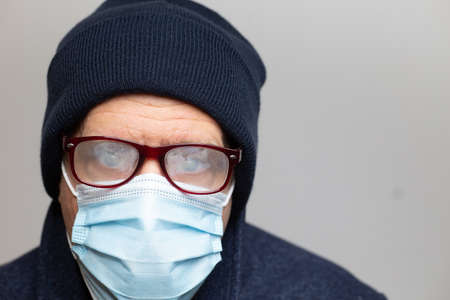 man with face mask, blue hat and foggy glasses close up with copy space. horizontalの写真素材