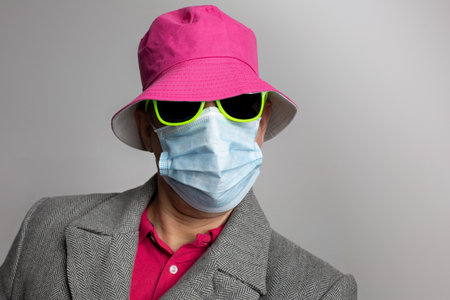 Portrait of man in pandemic times with pink hat and yellow sunglasses in corona measures