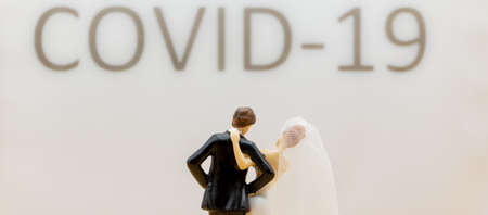 Bride and husband standing in front of a lettering with covid 19, celebrating without party guests because of corona. Horizontalの写真素材