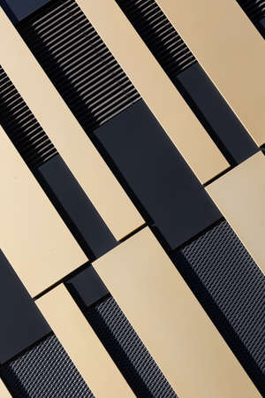 Abstract, modern house facade with gold-colored and black patterns from an oblique angle, as background to architecture. Verticalの写真素材