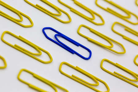 yellow paper clips that lie in one direction, a blue paper clip that goes away from its own unique and individual. Horizontalの写真素材