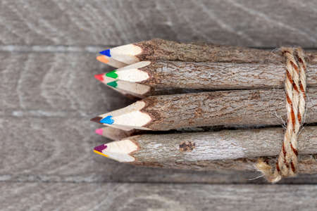 bound crayons made of real, untreated wood on top view with real tree bark on brown wooden board for artists, students and nature lovers. Horizontalの写真素材