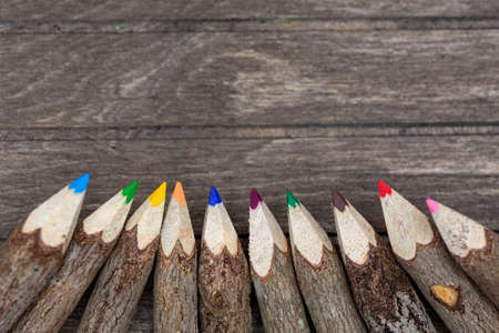 Crayons made of untreated wood, unique and with real tree bark on wooden board with copy space for students, artists. Verticalの写真素材