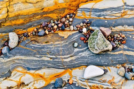 Colorful pebbles rest on wave eroded metamorphosed sedimentary rocks along the Pt. Lobos coast.