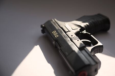 Umea, Sweden - September 4, 2019: a black gun lies in the window with sunlight streaming in from the nearest windowのeditorial素材