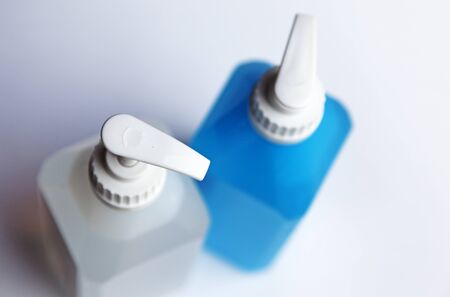 a white and a blue pump bottle with soap and hand spiritの写真素材