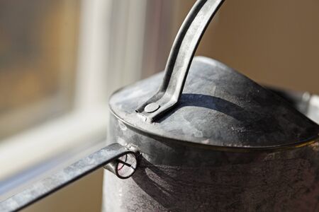 detail from a metal watering can standing in the windowの写真素材