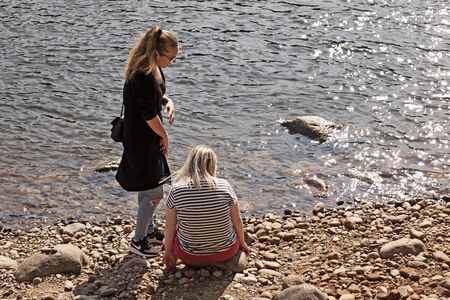 Umea, Norrland Sweden - August 29, 2019: enjoying the sun and picking stones at the river's beachのeditorial素材