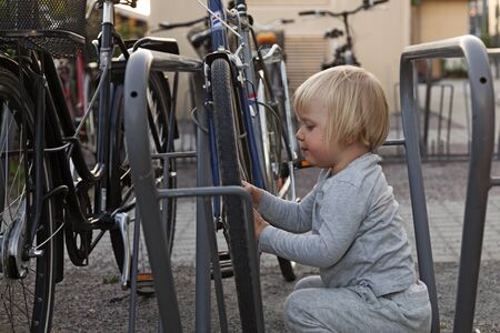 Uppsala, Sweden - June 28, 2019: a cute little boy inspecting the bikes in a parking lot near the train stationのeditorial素材