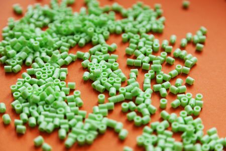 green indian beads on orange background, toy for kids who want to make necklacesの写真素材