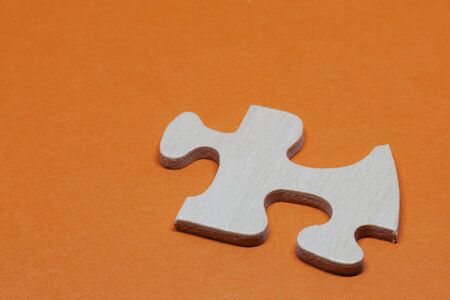 a puzzle piece in wood on orange backgroundの写真素材