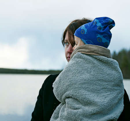 Umea, Norrland Sweden - May 7, 2020: mother holds baby in blanket by the lakeのeditorial素材