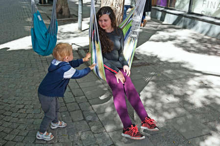 Ostersund, Norrland Sweden - July 15, 2020: little boy swings big sister on the pedestrian streetのeditorial素材