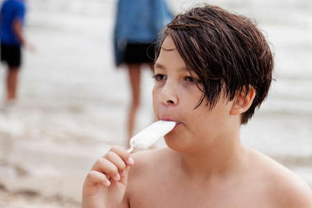 Umea, Norrland Sweden - June 26, 2020: young guy eating ice cream on the beachのeditorial素材