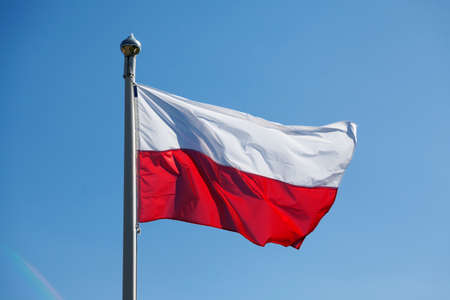 Poland's red and white flag on blue summer skyの写真素材