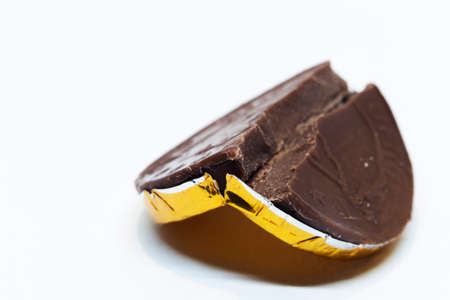 a chocolate coin broken in two on white background