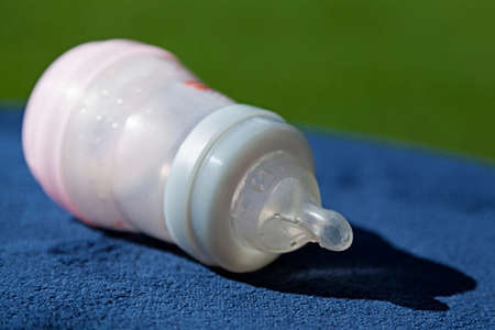 a baby bottle lying on a blue tableclothの写真素材