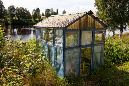 a small worn greenhouse by the riverの写真素材